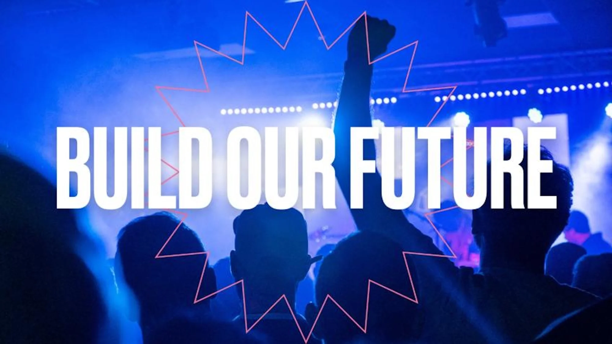 A Crowd at a Live music show, drenched in blue light, with one person with their fist raised in the air