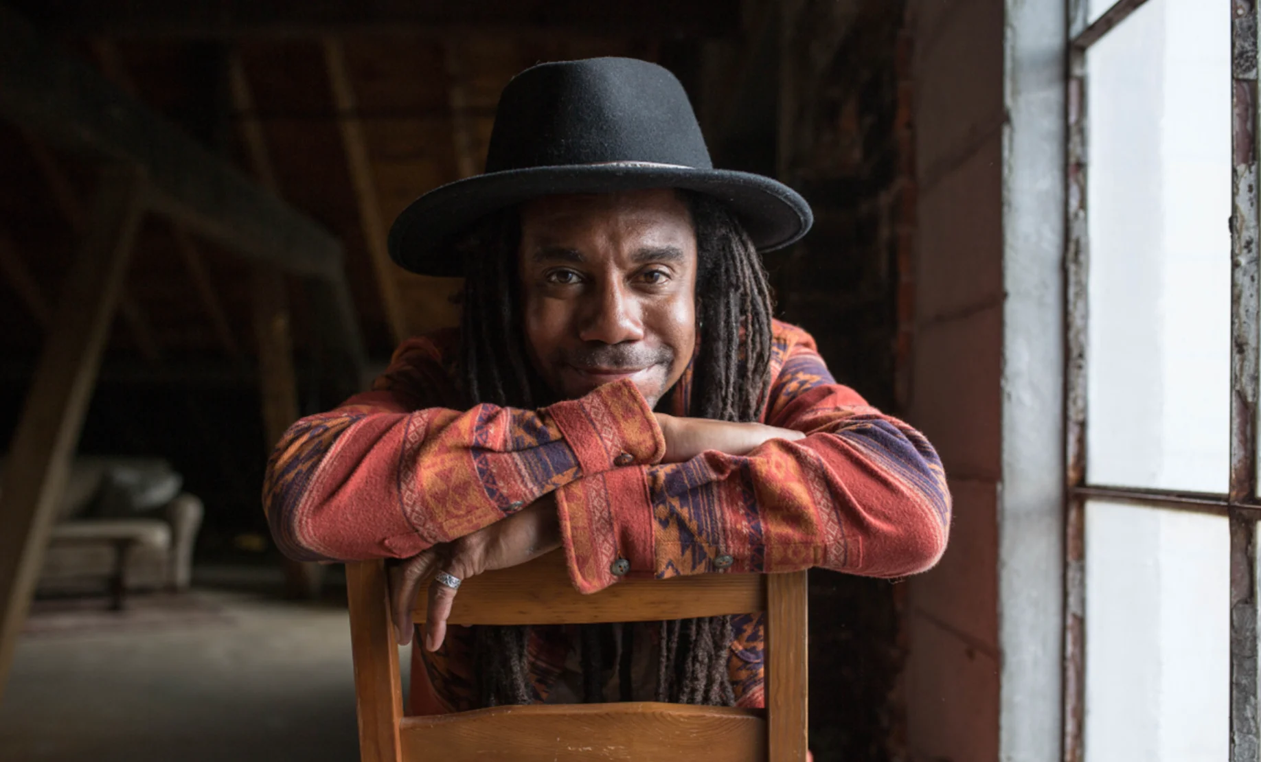 Julian Taylor sat on a chair backwards leaning over the back facing the camera